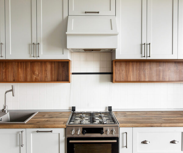 Stylish light gray kitchen interior with modern cabinets and stainless steel appliances. kitchen design in scandinavian style. contemporary cooker, wooden worktop, granite sink and stylish faucet